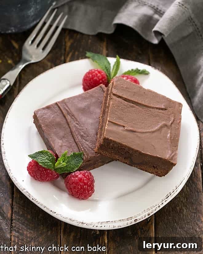 Decadent Chocolate Swirl Brownies 2 An overhead view of two exquisitely rich chocolate poke brownies presented on a classic round white dessert plate, inviting a decadent experience.