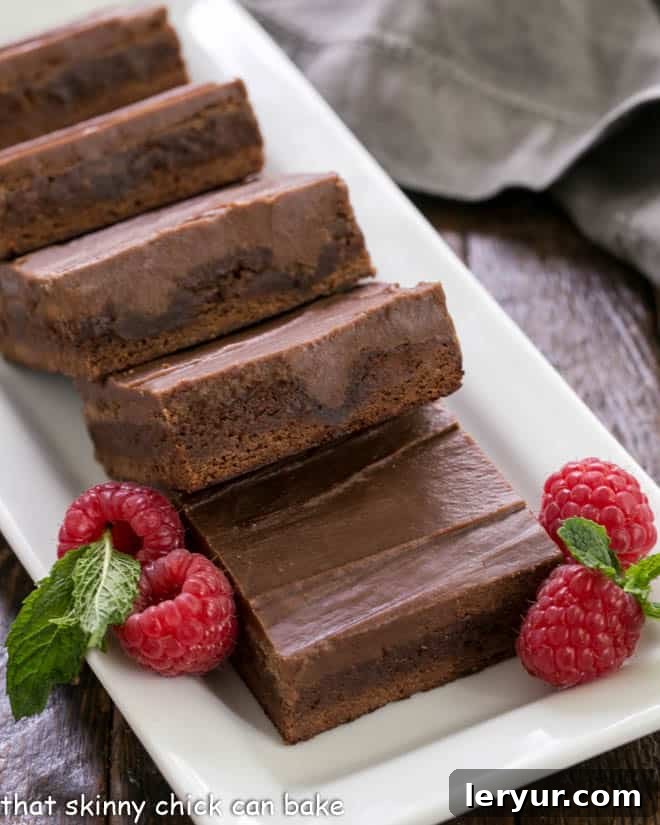 Decadent Chocolate Swirl Brownies 3 A close-up view of chocolate poke brownies, generously garnished with fresh raspberries, displayed on a elegant white serving tray, emphasizing their moist texture and irresistible appeal.