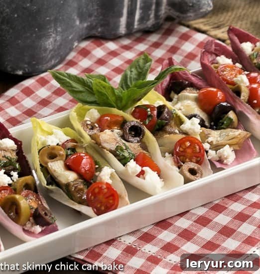 Mediterranean Endive Boats - a fun, bite sized salad or appetizer A white ceramic tray presenting various Mediterranean Endive Boats filled with a colorful salad.