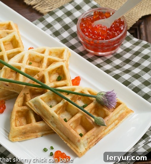 Smoked Salmon Waffles - Waffles with a savory twist! Smoked Salmon Waffles on a white platter with chives and salmon roe garnishes, ready to be served for brunch or as an appetizer.
