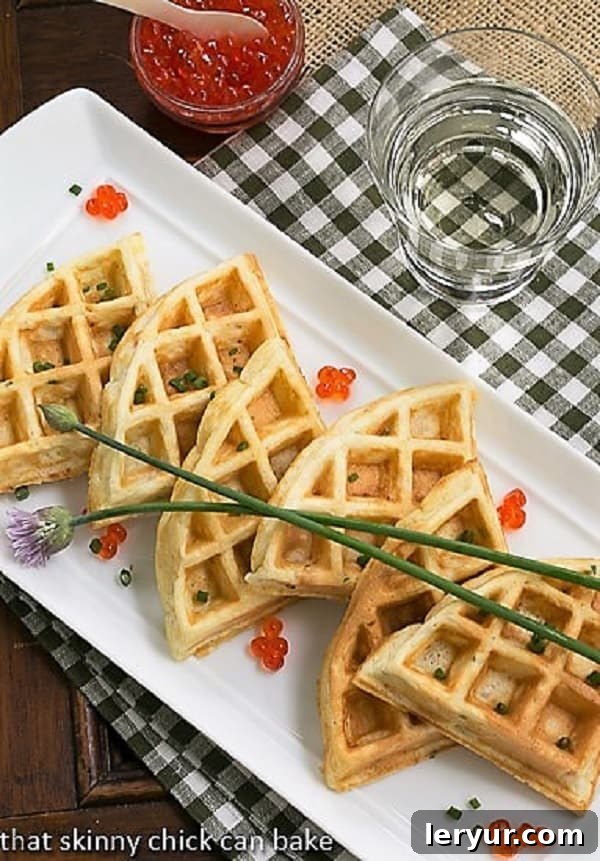 Smoked Salmon Waffles - Waffles with a savory twist! Smoked Salmon Waffles lined up on a white serving tray with chive blossoms and salmon roe, ready for an elegant brunch or party.