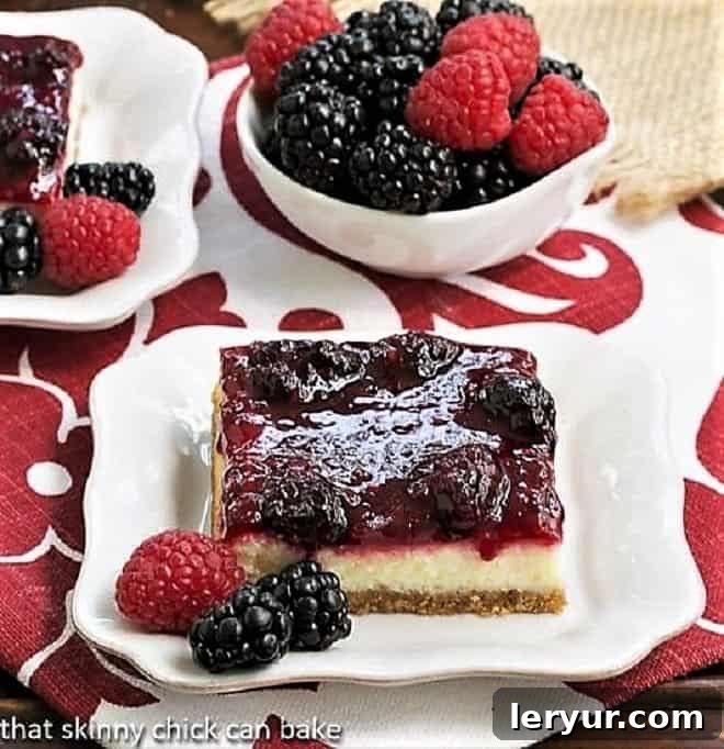 Berry Topped Cheesecake Bars sliced and served on white plates with berries