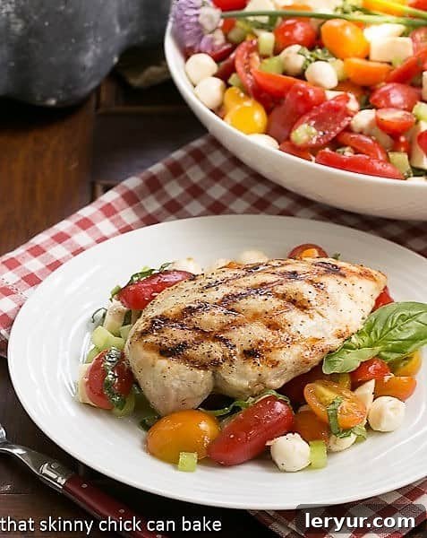 Grilled chicken breast over a Caprese Salad with Chicken, showcasing vibrant colors and fresh ingredients