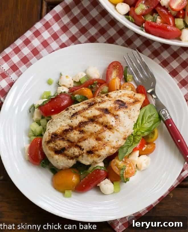 Overhead view of grilled chicken breast over a fresh Caprese salad, perfect for a summer meal