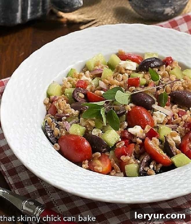 Delicious Greek Farro Salad with chewy farro, tomatoes, olives, cucumbers and more! A beautifully presented Greek Farro Salad in a rustic white basketweave bowl, ready for enjoyment.