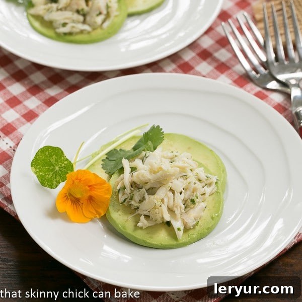Crab Avocado Ravioli - An elegant, delectable crab salad presentation! Close-up of Crab Avocado Ravioli slices arranged on a white plate with a delicate flower garnish, emphasizing its freshness and elegant plating.