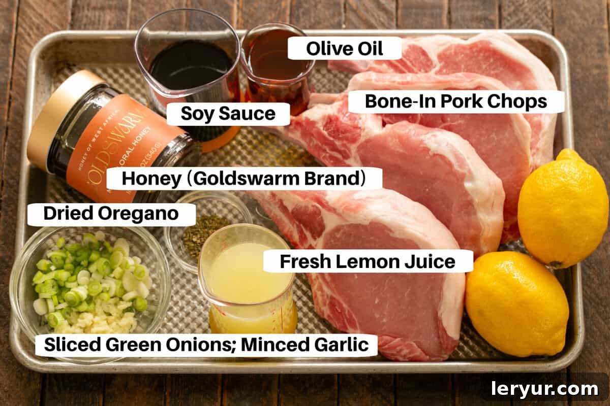 A selection of fresh ingredients for the soy, honey, and lemon pork chop marinade, meticulously arranged on a sheet pan with clear labels.