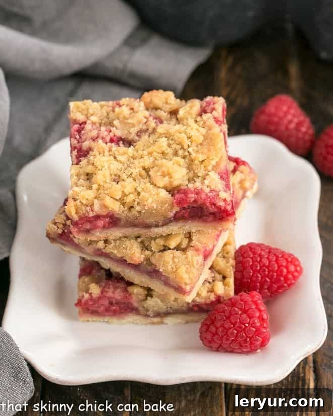 Streusel Topped Raspberry Squares on a small square white plate, showcasing their beautiful layers