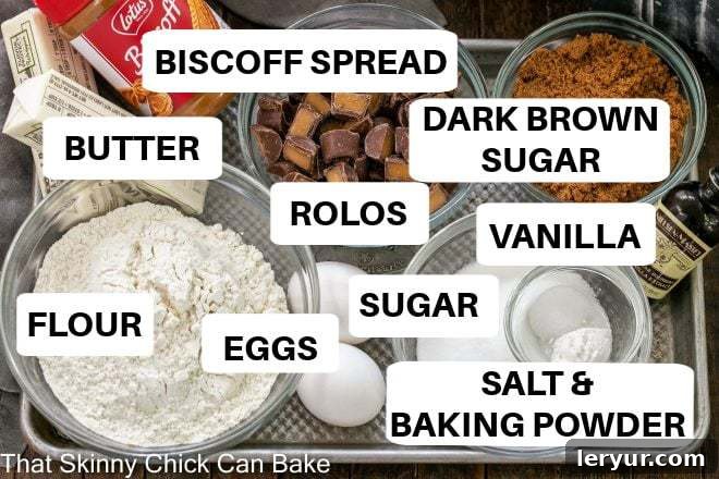 A collection of Biscoff Rolo Bar ingredients, including butter, sugar, eggs, Biscoff spread, flour, baking powder, and Rolo candies, neatly arranged on a metal tray.