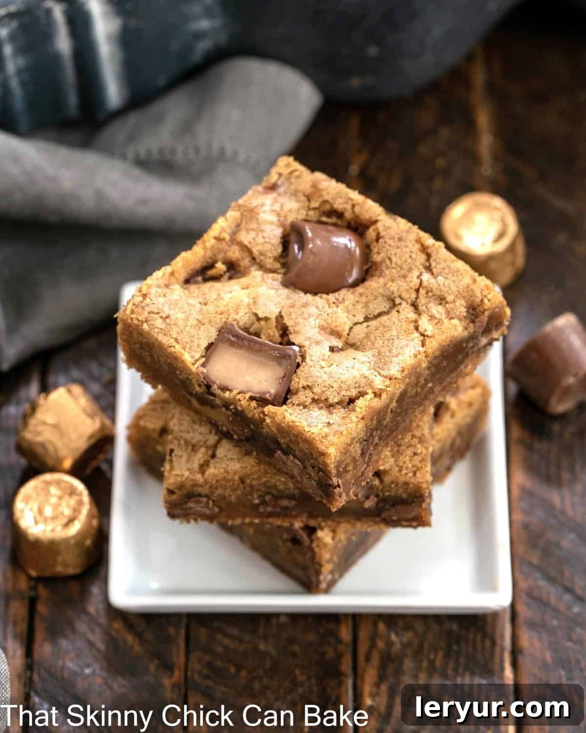 A stack of three Biscoff Rolo Bars rests on a small, elegant square white plate, showcasing their inviting texture and rich fillings.