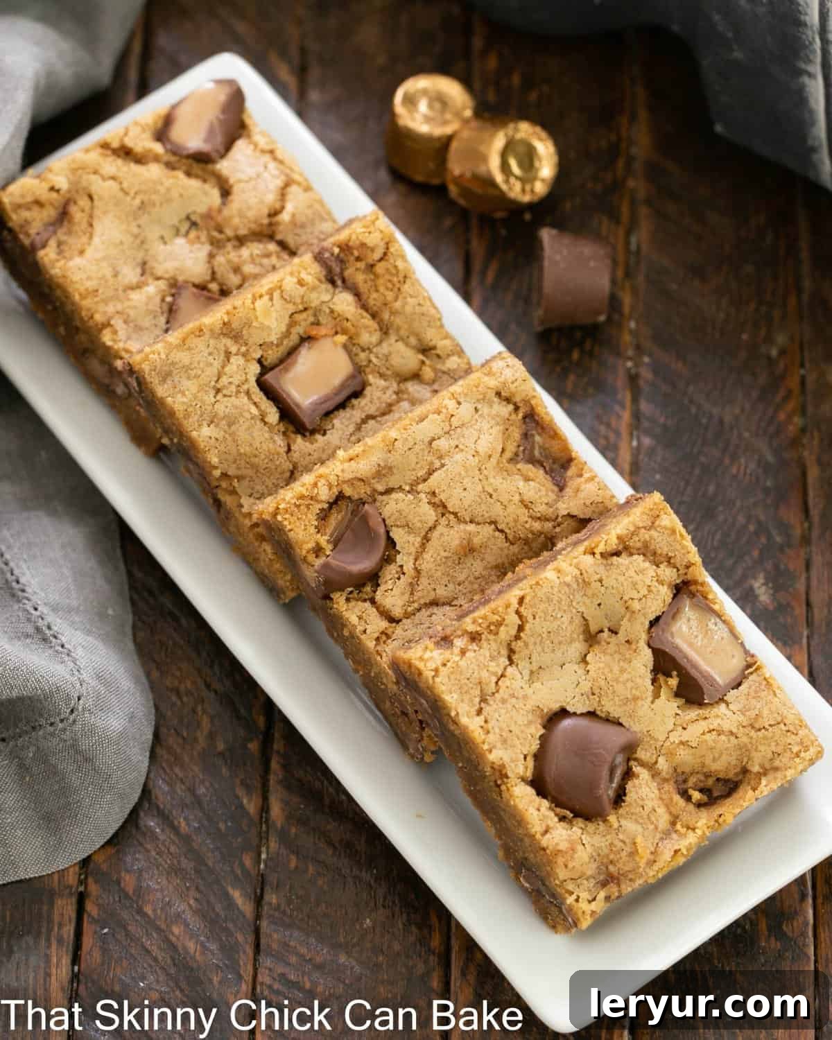 An overhead view of a full tray of freshly baked Biscoff squares, perfectly cut and arranged on a pristine white ceramic tray, ready for serving.