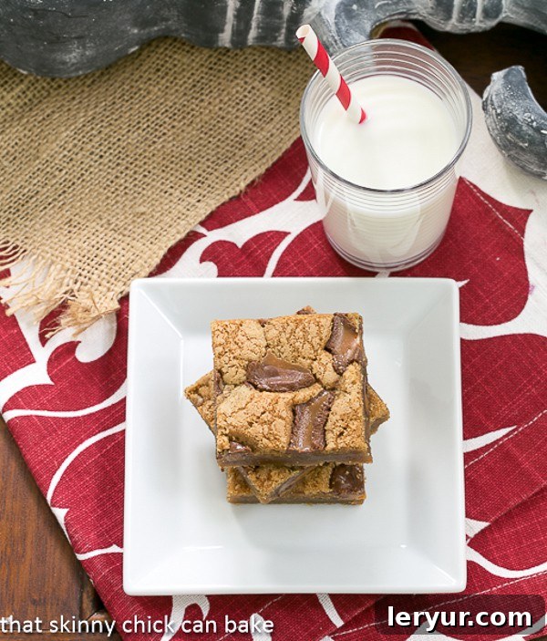 Two Biscoff Rolo Bars stacked invitingly on a square white plate, accompanied by a refreshing glass of milk, creating a classic dessert scene.