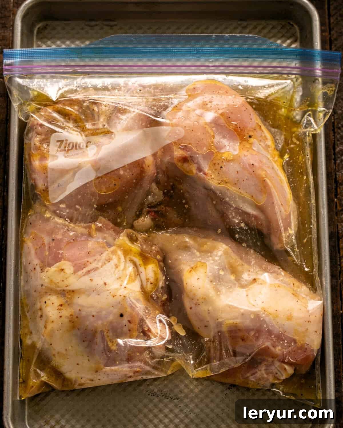 Zesty Mustard Lime Chicken 4 Chicken breasts with marinade in a large Ziploc bag, placed on a sheet pan for marinating.