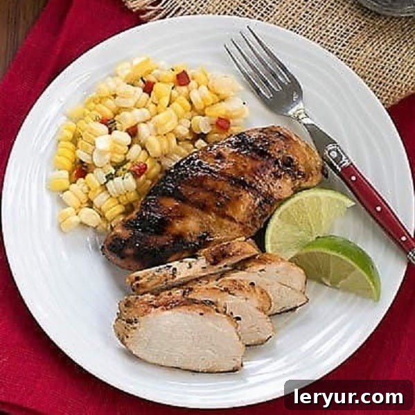 Mustard, Garlic, Lime Marinated Chicken Breasts is flavored with the BEST chicken marinade! Overhead view of a white dinner plate featuring perfectly grilled marinated chicken, fresh lime wedges, and vibrant green asparagus.