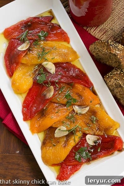 Sweet & Smoky Roasted Peppers 3 Overhead view of glistening Oven Roasted Peppers with aromatic garlic slices and fresh herbs on a pristine white platter.