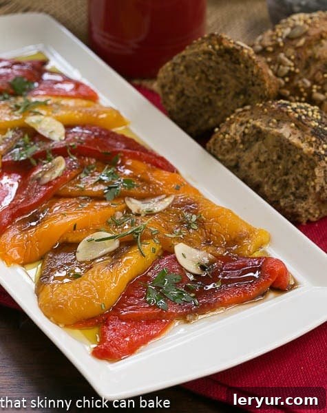 Sweet & Smoky Roasted Peppers 4 A close-up view of a vibrant assortment of Oven Roasted Peppers, glistening with olive oil and herbs, presented on a rustic white tray.