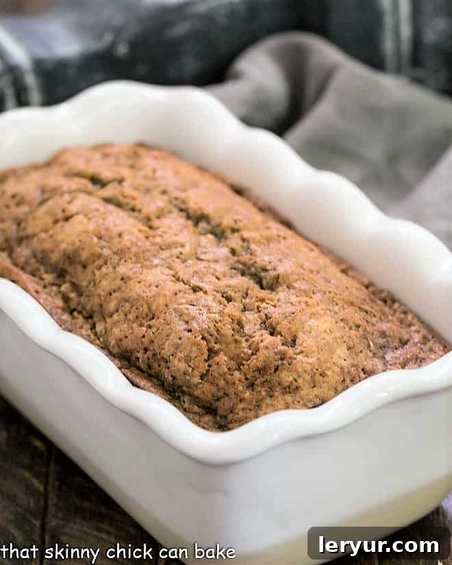 Classic Zucchini Bread is tender, moist with a touch of cinnamon for an irresistible snack, breakfast or even dessert! Loaf of Cinnamon Spiced Zucchini Bread Recipe in a white loaf pan.