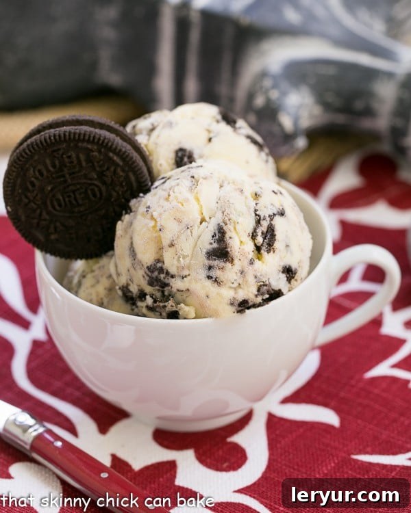 Homemade Oreo Ice Cream - Dreamy homemade vanilla ice cream with generous chunks of Oreo cookies! Two scoops of homemade Oreo Ice Cream in a teacup, garnished with a whole Oreo cookie, showcasing its creamy texture and cookie chunks.