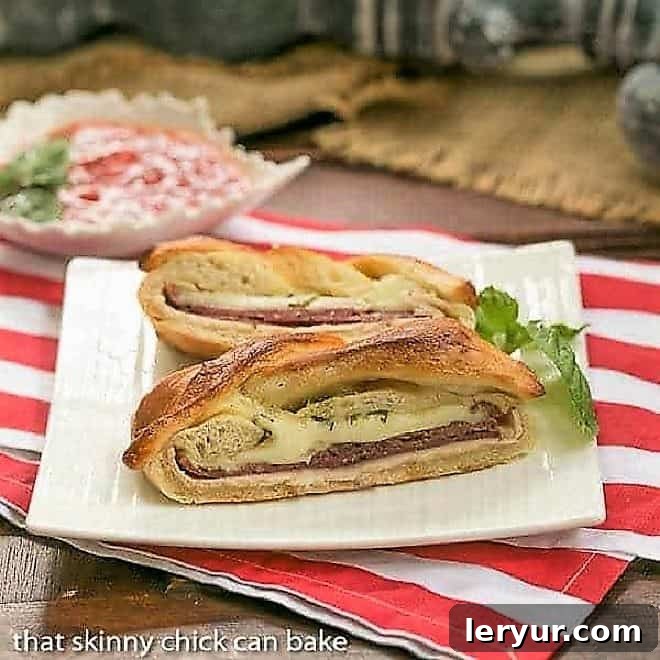A beautifully braided stromboli, golden brown and glistening, rests on a pristine square white plate, garnished with a fresh sprig of basil. Steam subtly rises, hinting at the warm, savory filling within. Ideal for game day or a family meal.