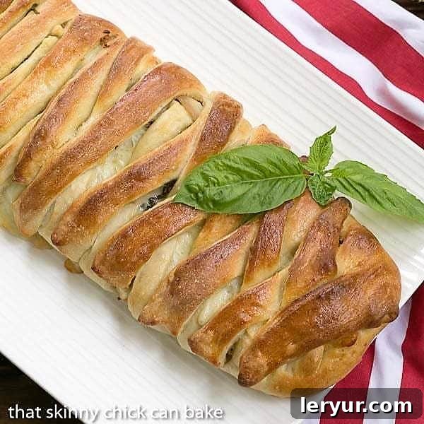 An overhead view of a freshly baked, golden-brown braided stromboli, perfectly sliced to reveal its rich, savory fillings of Italian meats and melted cheeses, served on a pristine white platter. A truly appetizing game day treat or family dinner.