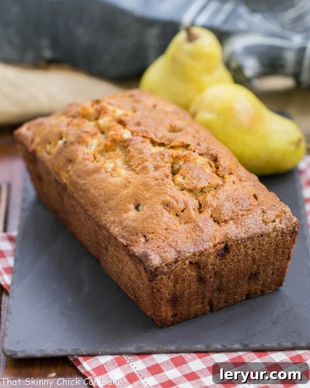 Sour Cream Pear Bread - A delectable autumn quick bread with subtle warm spices and chunks of fresh pears Loaf of Sour Cream Pear Bread on a slate board, ready to be sliced.