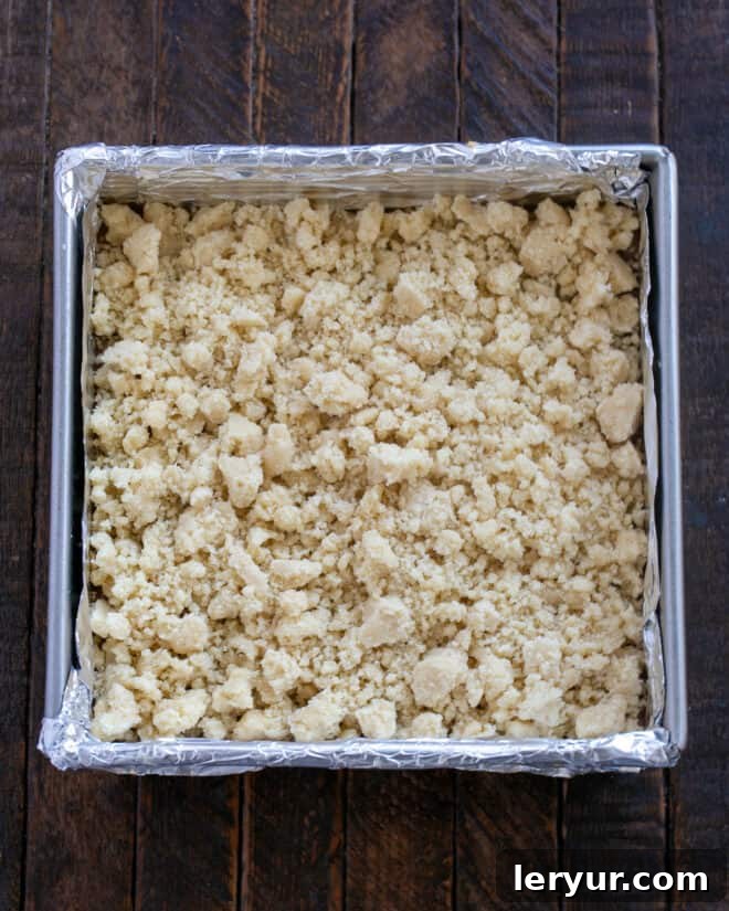 Golden Caramel Squares 10 Remaining dough is being crumbled over the caramel layer.