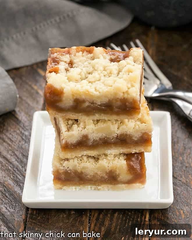 Caramel Butter Bars - Simple flavors with delicious results! This Caramel Dessert is easy to make and perfect for caramel lovers!! Three beautifully stacked Caramel Butter Bars on a small white plate, showing off their golden crust and gooey caramel center.