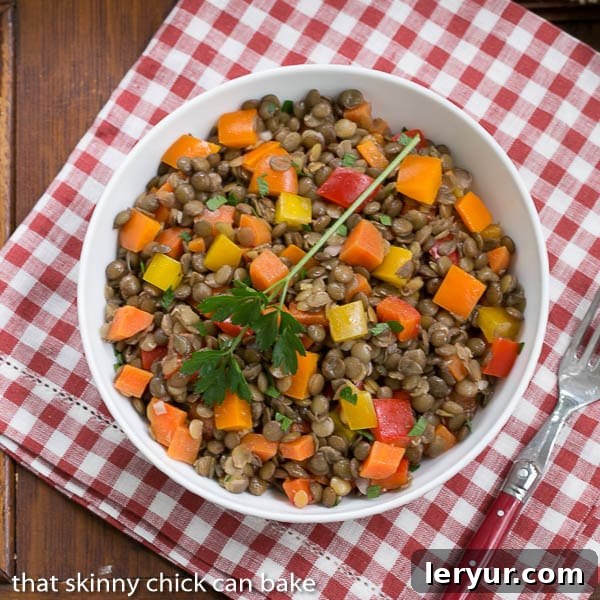 French Lentil Salad presented in a white serving bowl, resting elegantly on a classic red and white checkered napkin, evoking a rustic, homey charm.