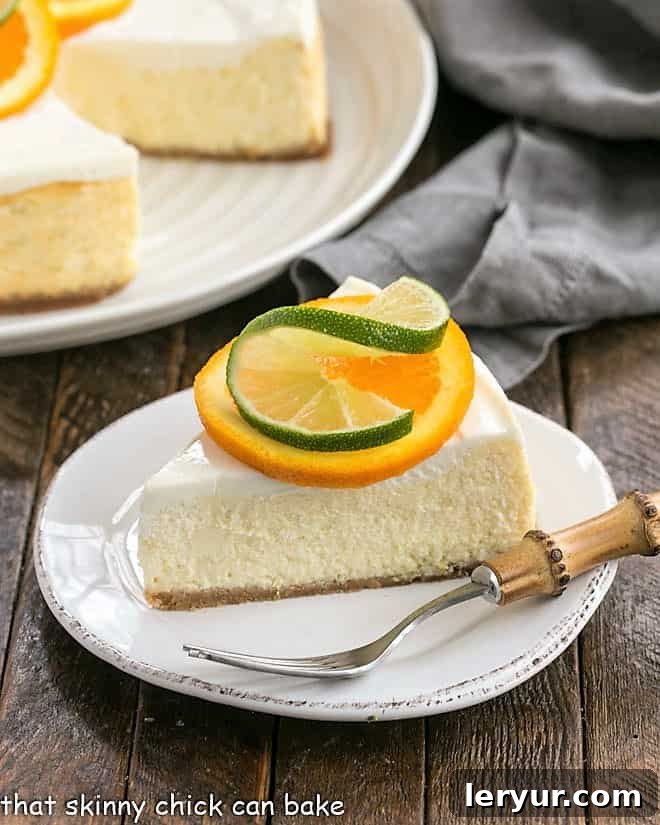 Margarita Cheesecake slice on a white dessert plate garnished with an orange and lime slice.