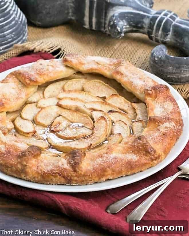 Maple Glazed Apple Galette on a white serving plate on a red napkin, showcasing its golden crust and glistening apple slices.