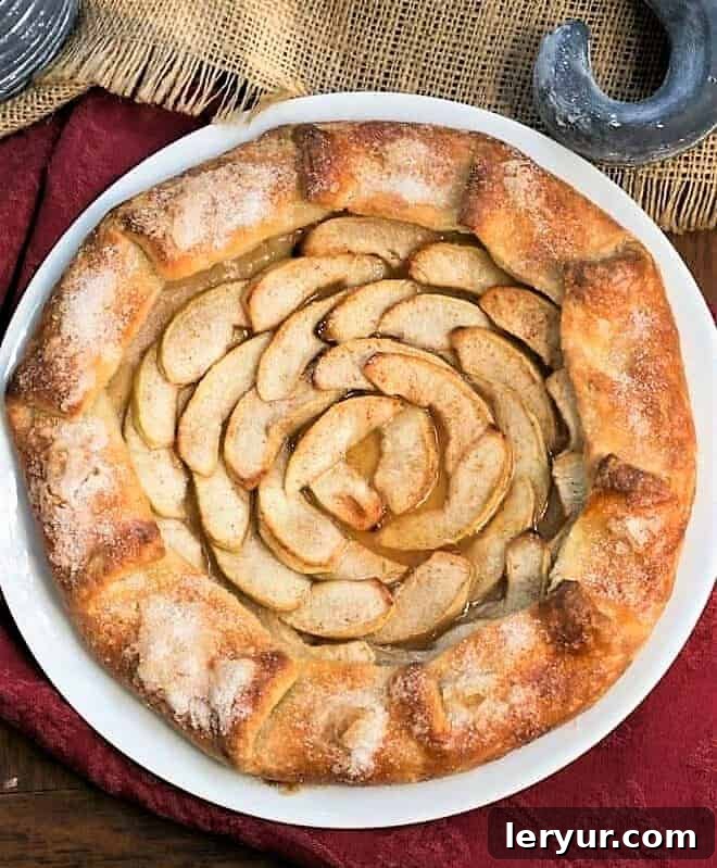 Overhead view of a Maple Glazed Apple Galette on a white ceramic serving plate, highlighting the perfectly arranged apple slices.