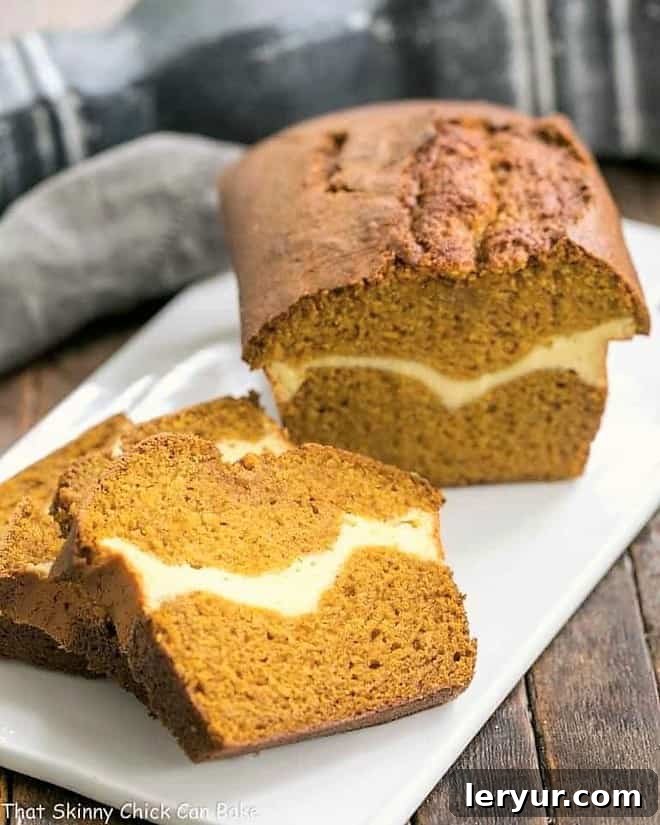 Cream Cheese Filled Pumpkin Bread -A moist, delicious pumpkin loaf with a ribbon of cream cheese in the middle! Cream Cheese Filled Pumpkin Bread on a white ceramic board with sliced pieces.