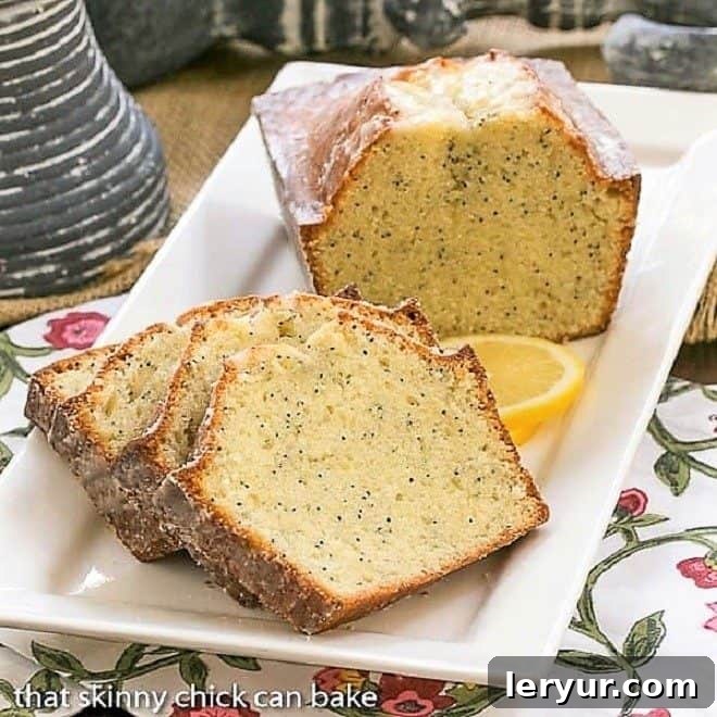 Glazed Poppy Seed Bread - tender, sweet and flavored with vanilla and almond extracts! Slices of Glazed Poppy Seed Bread and half a loaf on a white ceramic tray