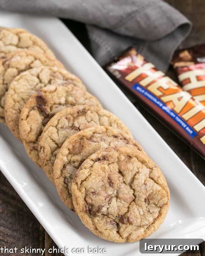 Brown Butter Toffee Cookies - Chewy cookies filled with toffee chunks with a nutty nuance thanks to brown butter! Toffee Cookies on a white tray, showcasing their golden edges and delicious texture.
