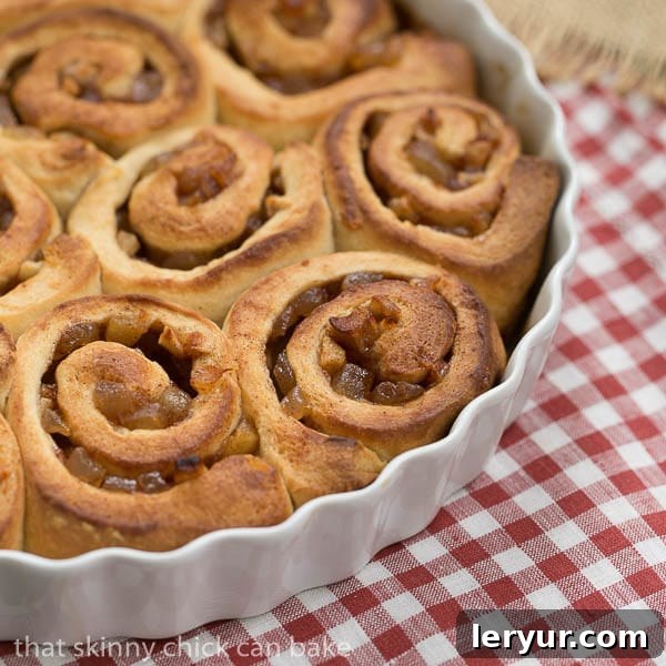 Apple Cinnamon Rolls - bits of apples rolled into this breakfast treat make them irresistible!!! Unfrosted Apple Cinnamon Rolls arranged neatly in a round white baking dish, ready for glazing.