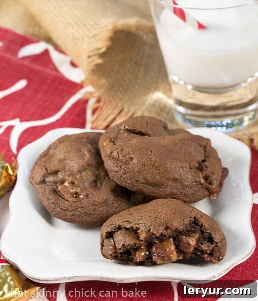 Double Chocolate Twix Cookies - rich, chocolate cookies filled with chunks of decadent Twix bars! A Double Chocolate Twix Cookie broken open, revealing the luscious caramel and cookie pieces from inside the Twix bar.