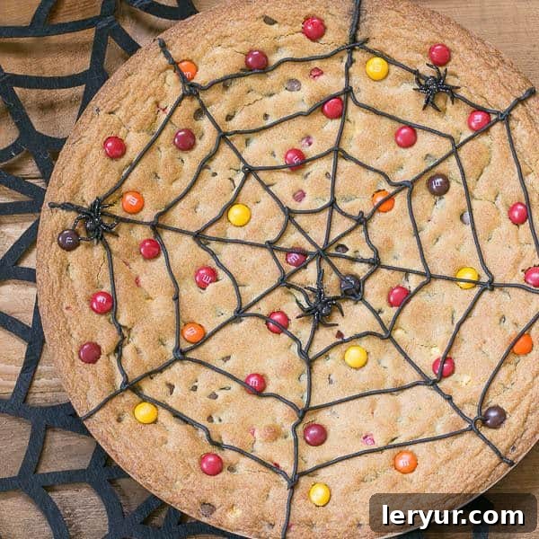 Spiderweb Cookie Cake topped with M&M's on a felt spiderweb, ready for a Halloween party.