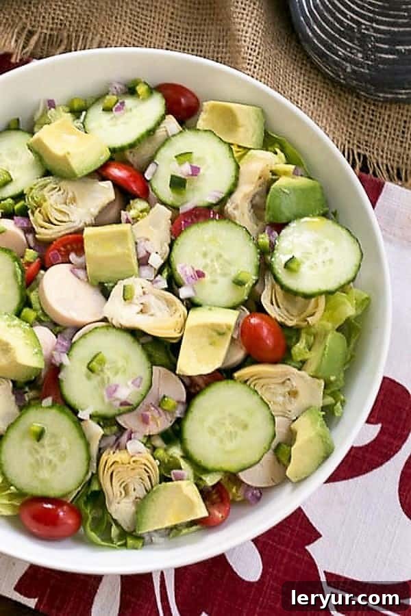 Hearts of Palm, Artichoke, Avocado and Butter Lettuce Salad - an irresistible, refreshing salad! A close-up overhead view of the colorful Hearts of Palm, Artichoke, Avocado, and Butter Lettuce Salad in a white serving bowl, highlighting the fresh ingredients.