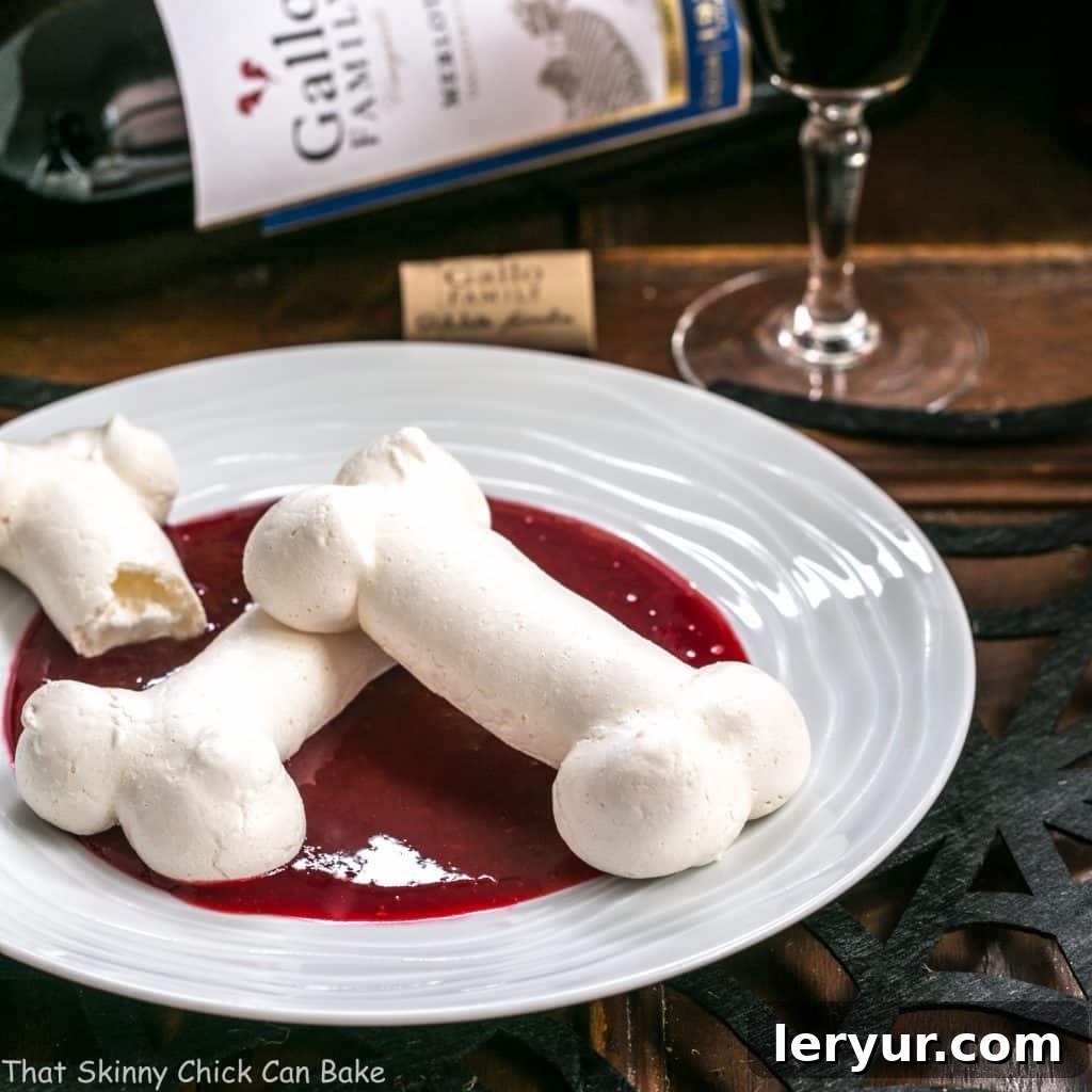 Meringue Bones artfully arranged on a white plate, with a bottle of wine in the background, suggesting an elegant adult Halloween treat.