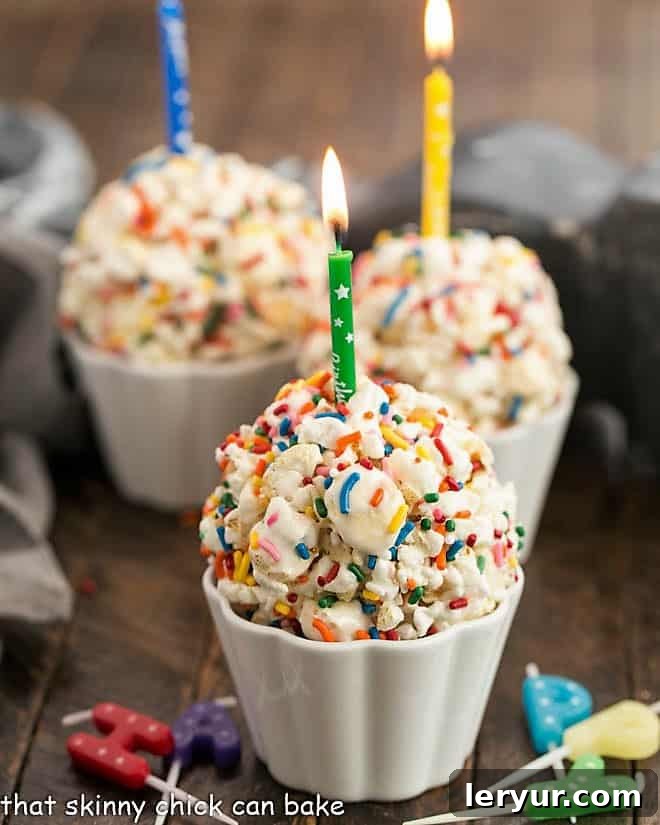 Easy Marshmallow Popcorn Balls - A simple popcorn treat that's great for all ages! Easy Marshmallow Popcorn Balls in white ramekins topped with lit candles, ready for celebration.