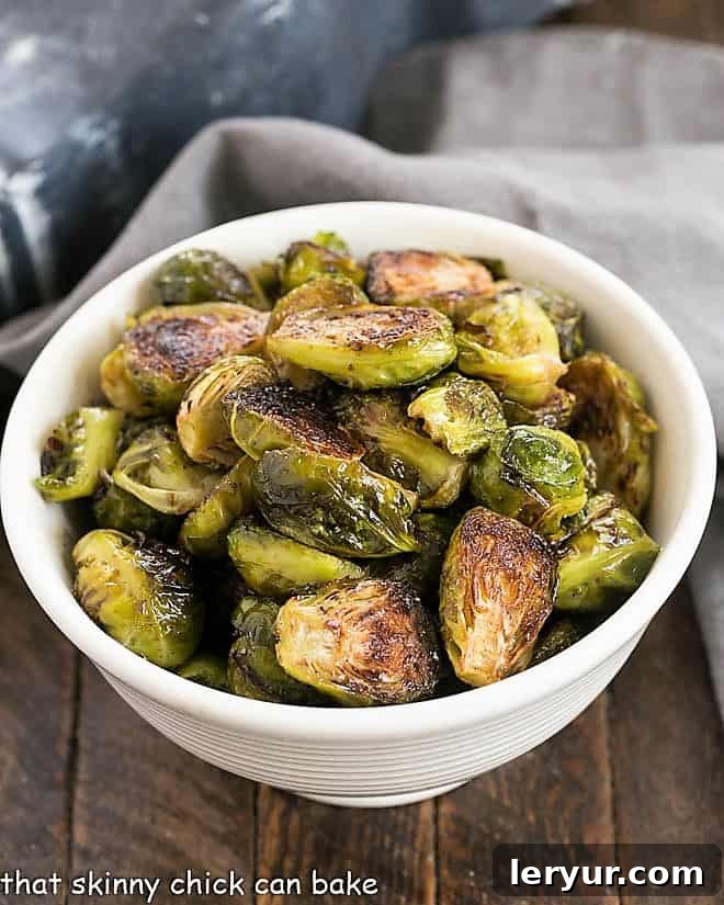Roasted Brussels Sprouts Recipe - Turn these once dreaded vegetables into one amazing, sweet and savory side dish by roasting and tossing in a delicious vinaigrette Overhead shot of vibrant Honey Balsamic Brussels Sprouts in a white serving bowl, garnished and ready to eat.
