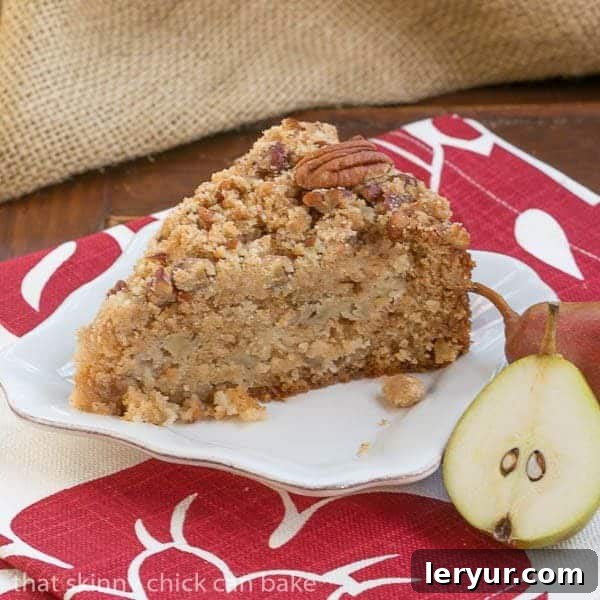Pear Streusel Coffee Cake - A moist, tender, crumb topped coffee cake that's perfect for company! A perfectly baked slice of Pear Streusel Coffee Cake, presented on a minimalist square white plate, accompanied by a fresh pear half and a delicate serving fork.