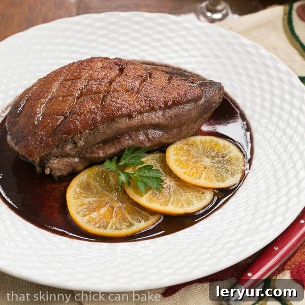 Elegant Pan Seared Duck Breasts with Clementines and Red Wine Sauce - A Foolproof Recipe for Special Occasions Pan Seared Duck Breasts on a white basketweave plate, garnished with clementine slices and fresh herbs.