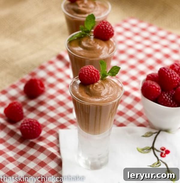 Chocolate Mousse with Grand Marnier in small glasses each topped with a raspberry and mint. Chocolate Mousse with Grand Marnier served in small individual glasses, garnished beautifully with fresh raspberries and a sprig of mint.