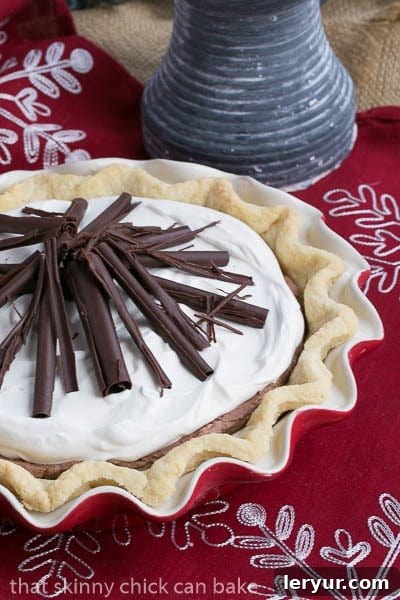 Chocolate Mousse Pie Recipe - A layered chocolate sensation! A pristine, uncut Black Bottom Chocolate Mousse Pie nestled in a vibrant red pie plate, artfully garnished with a generous scattering of chocolate curls.