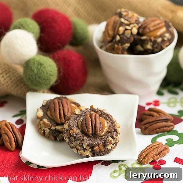 Delicious Thumbprint Cookie Recipe - chocolate cookies filled with caramel and pecans. A close-up shot of a single Turtle Thumbprint Cookie resting on a small white ceramic plate, with a bowl of more cookies in the background, highlighting the beautiful caramel center and pecan topping.