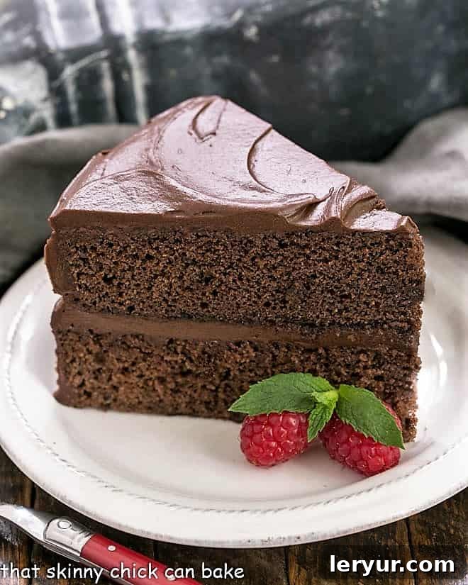 Slice of Devil's Food Cake on a white plate with berries and mint