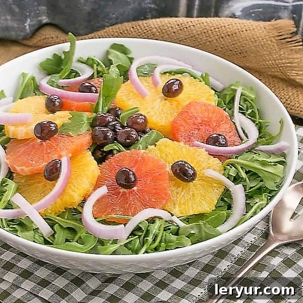 Refreshing Orange Olive Salad served on a bed of fresh arugula in a pristine white bowl, ready to be enjoyed.