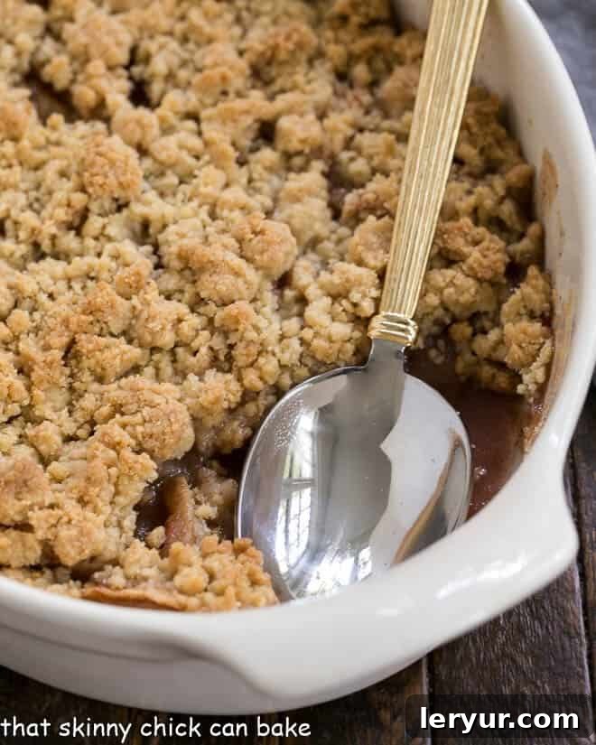 Easy Apple Crisp in a white ceramic baking dish with a serving spoon.