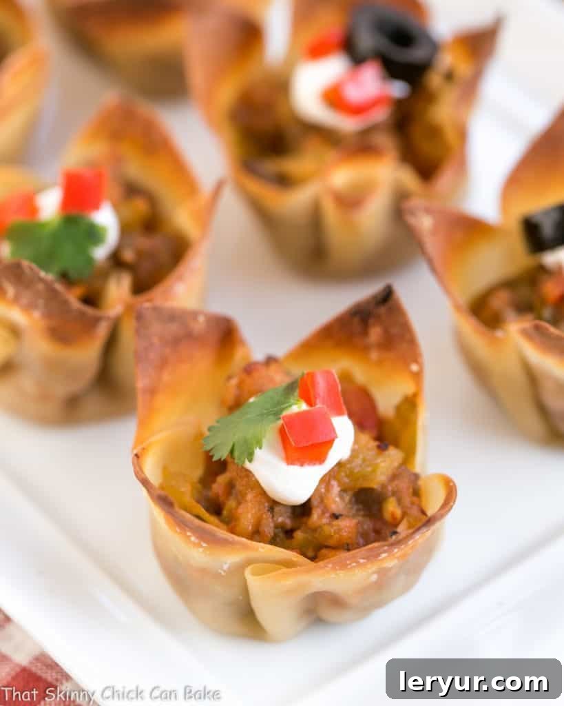 Mini Mexican Tarts - Crispy Shells filled with spiced sausage and cheese create delicious, spicy sausage appetizers Closeup of Mini Mexican Tarts on a white tray, showcasing their crispy shell and savory filling.
